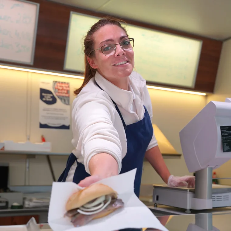 Frisch zubereitetes Heringsbrötchen wird über die Theke gereicht